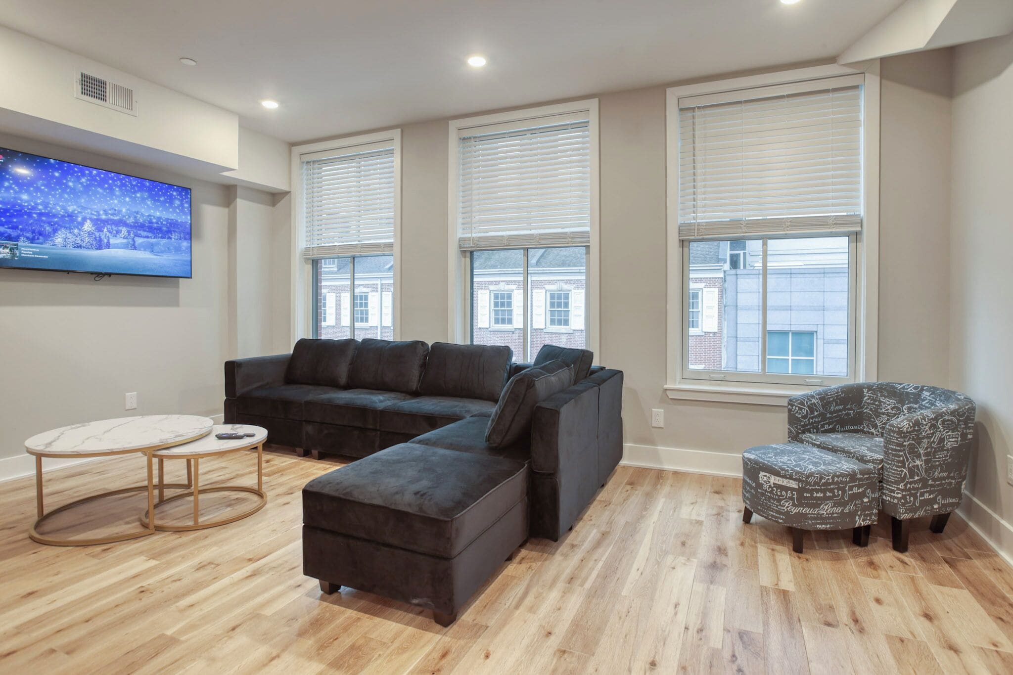 A modern living room with a sectional sofa, ottoman, and a small round table.