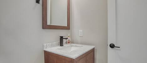 A bathroom with a marble sink, wooden vanity, and a mirror with a wooden frame.
