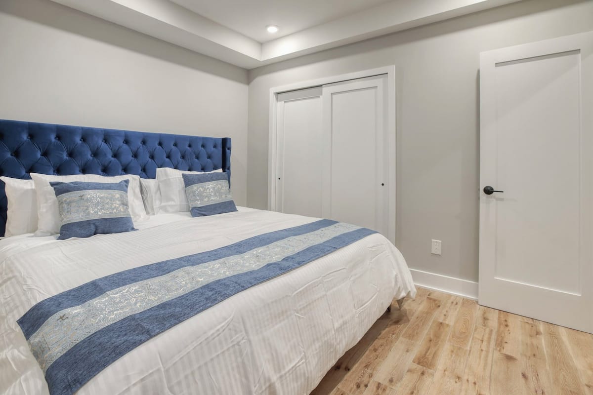 A bedroom with a large bed, a tufted headboard, and a white door.