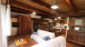 A rustic interior with a wooden ceiling, a stone fireplace, a white sofa, and a wooden dining table. - Gîte ST Saturnin, Cézallier, Monts du Cantal, Santoire Valley (Saint-Saturnin)