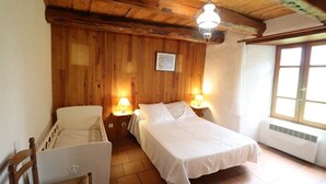 A cozy room with wooden walls, a bed, a chair, and a desk with a laptop. - Gîte ST Saturnin, Cézallier, Monts du Cantal, Santoire Valley (Saint-Saturnin)
