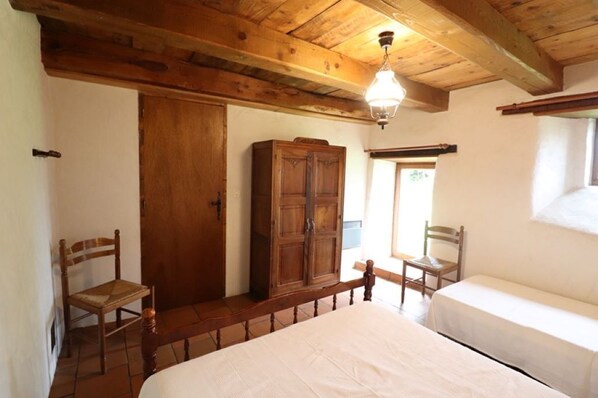 A bedroom with a wooden ceiling, a wardrobe, two chairs, and a bed. - Gîte ST Saturnin, Cézallier, Monts du Cantal, Santoire Valley (Saint-Saturnin)