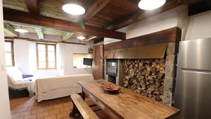 A cozy kitchen with a wooden table, a built-in stove, and a refrigerator. - Gîte ST Saturnin, Cézallier, Monts du Cantal, Santoire Valley (Saint-Saturnin)