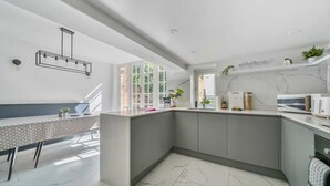 A modern kitchen with a marble floor, a built-in island, and a dining area with a polka dot tablecloth. - Georgian Coach House in a Prime Location in Deal (Kent)