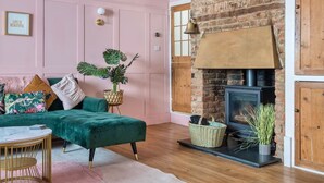 A cozy living room with a green sofa, a round coffee table, and a brick fireplace. - Georgian Coach House in a Prime Location in Deal (Kent)
