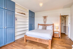Restful king bedroom with generous blue wardrobes and warm oak floors