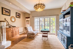 A spacious room with a large window, a wooden cabinet, a wicker sofa, and a billiards table. - Spacious 5-bedroom home with cinema room, Aga kitchen & forest walks (East Boldre)