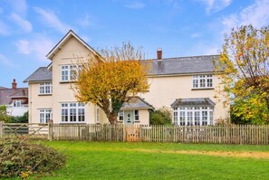 A two-story house with a front garden and a wooden fence. - Spacious 5-bedroom home with cinema room, Aga kitchen & forest walks (East Boldre)