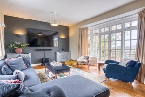 A modern living room with a sofa, armchair, and a television.