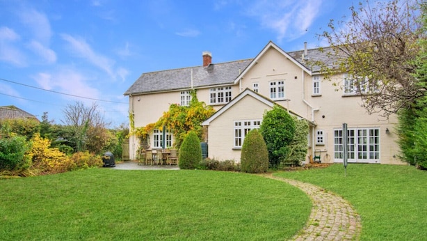 A two-story house with a well-maintained lawn and a paved driveway leading to the front door.