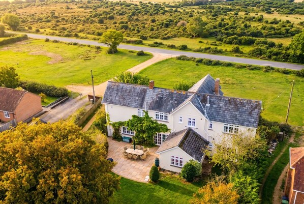 A large house with a spacious patio and a driveway leading to a road.