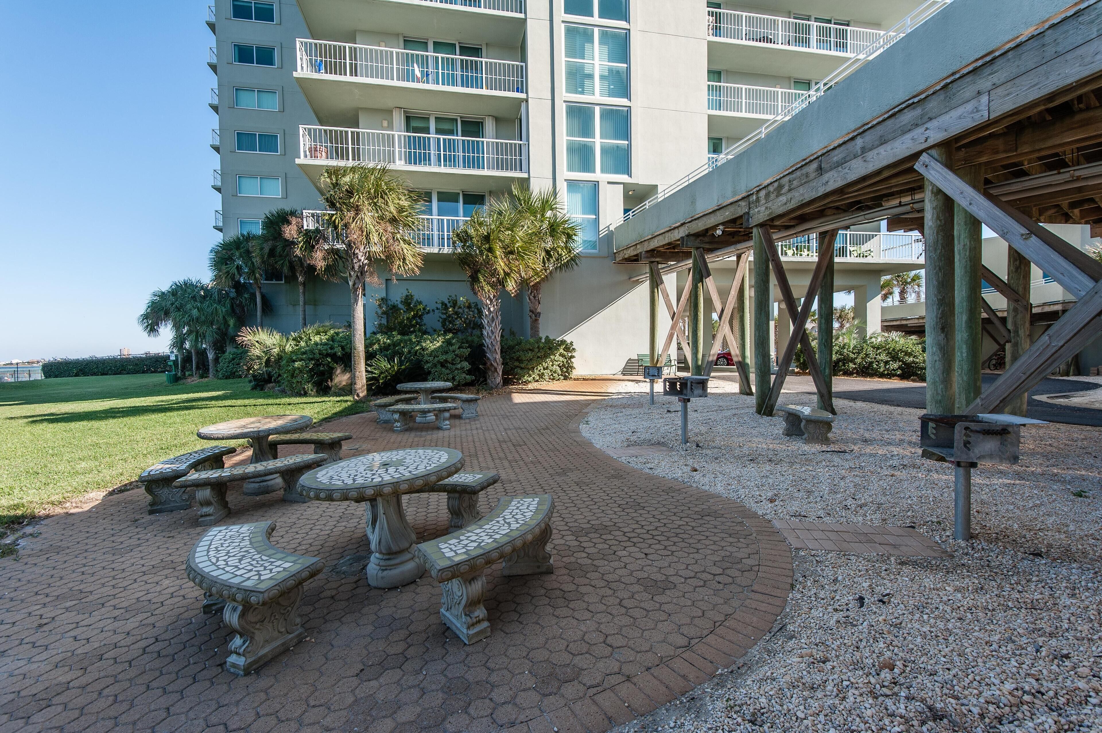 A courtyard with outdoor seating, palm trees, and a building with balconies.