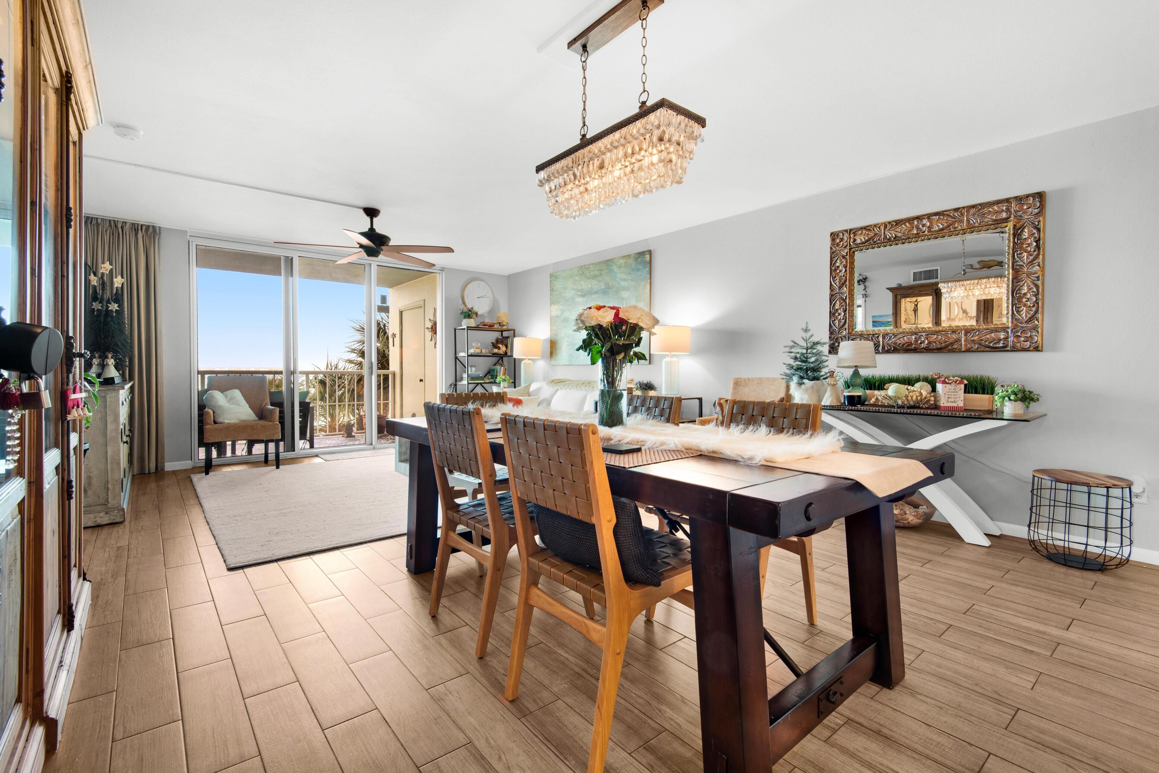 A dining area with a wooden table and chairs, a chandelier, and a large mirror on the wall.