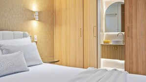 Un dormitorio con cama, armario de madera y baño con lavabo y espejo.