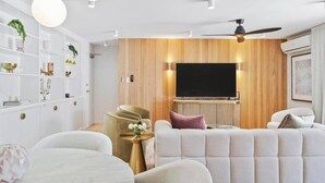 Un salón moderno con un panel de madera, un televisor de pantalla plana y un ventilador de techo.