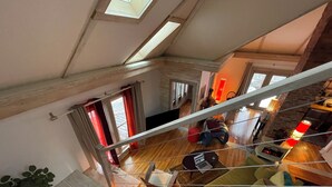 Amplia sala de estar con una escalera de madera, un sofá, una mesa de centro y una chimenea.
