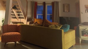 Una sala de estar estilo loft con techo alto, ventilador de techo, escalera y un sofá grande.