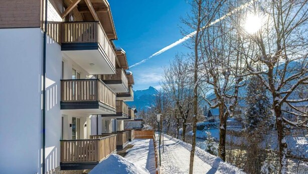 A row of modern multi-story buildings with balconies, set against a snowy landscape with mountains in the background. - Charming Apartment in Salzburg Without Deposit (Bad Hofgastein)