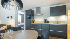 A modern kitchen with grey cabinets, a built-in oven, and a stainless steel range hood. - Charming Apartment in Salzburg Without Deposit (Bad Hofgastein)