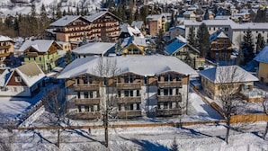 A snow-covered mountain town with a prominent multi-story building labeled "ALPINA" in the center. - Charming Apartment in Salzburg Without Deposit (Bad Hofgastein)