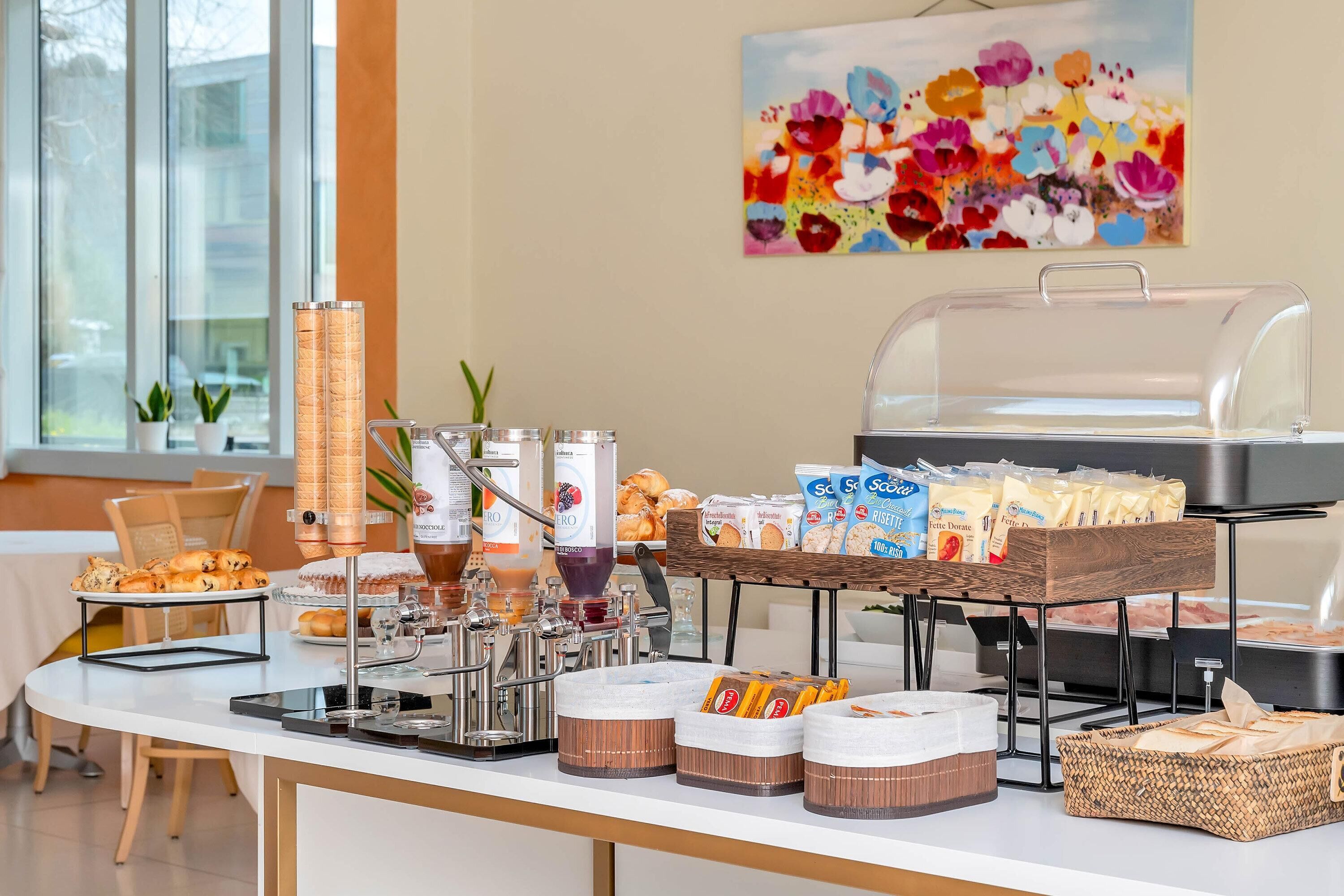 Een buffetopstelling met diverse soorten eten, waaronder gebak, dranken en verpakte snacks.