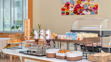 Een buffetopstelling met diverse soorten eten, waaronder gebak, dranken en verpakte snacks.