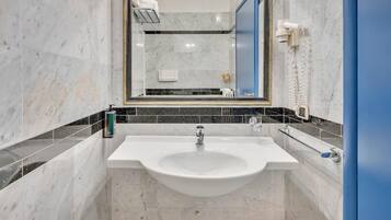Un bagno con un lavandino bianco, uno specchio e un asciugacapelli montato sulla parete.