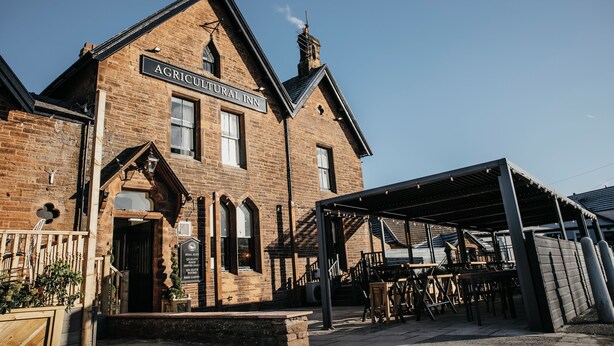 A brick building with a sign reading "AGRICULTURAL INN." - Agricultural Inn (Penrith)
