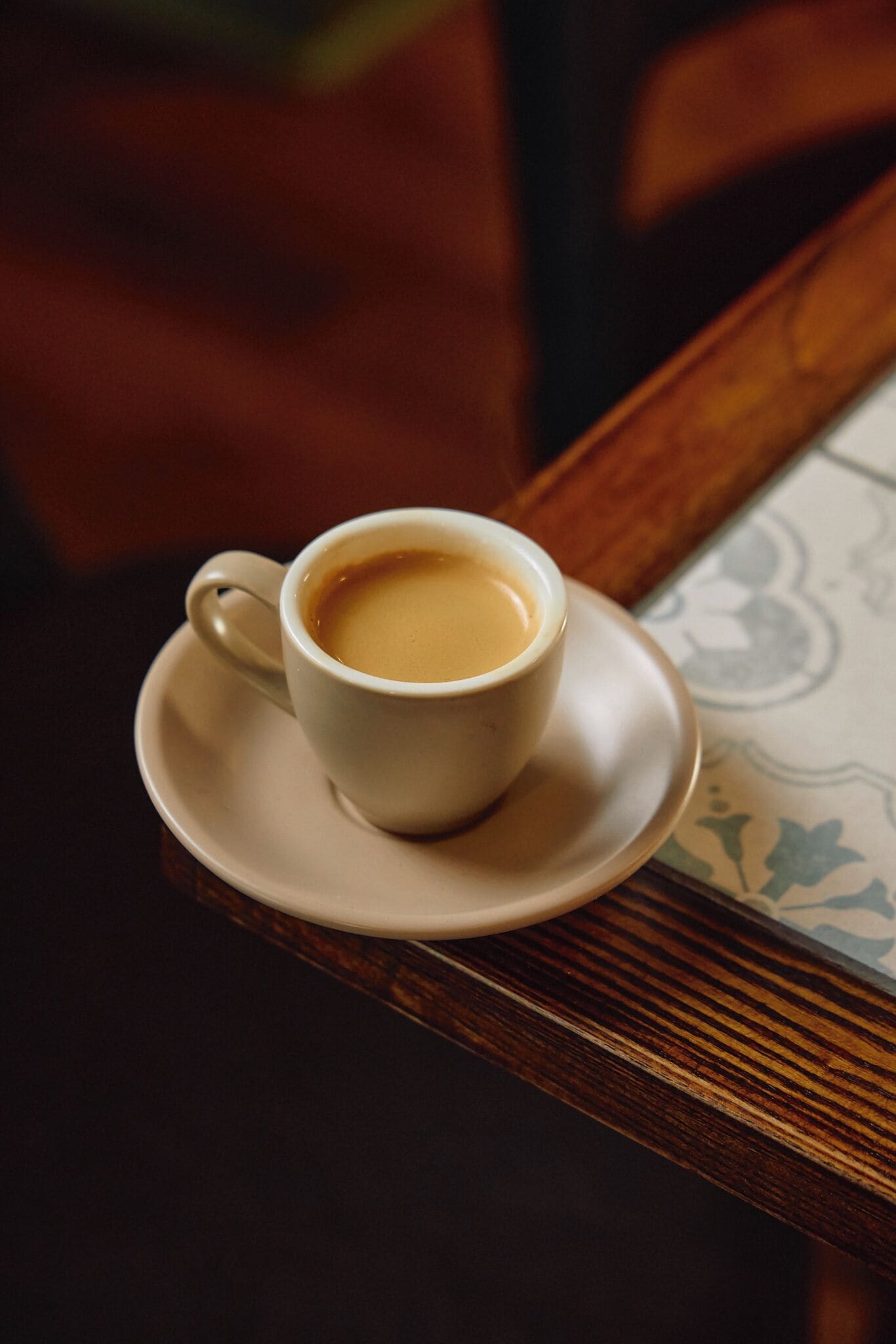 A cup of coffee on a saucer on a table.
