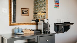 A kitchenette with a coffee machine, a small shelf with cups and a knife block, a mirror, and a wall-mounted sign. - Agricultural Inn (Penrith)