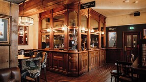 A bar area with wooden paneling, a bar counter, and seating. There are signs indicating directions to the garden area and other rooms. - Agricultural Inn (Penrith)
