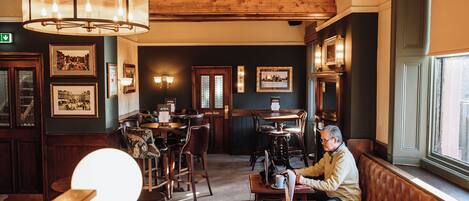 Un acogedor interior de restaurante con muebles de madera, una lámpara de araña grande y cuadros en las paredes.