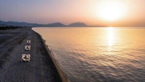 A beach with four tents aligned in a row, a calm sea, and mountains in the background. - Aethrion Luxury Villas & Suites (Rhodes)