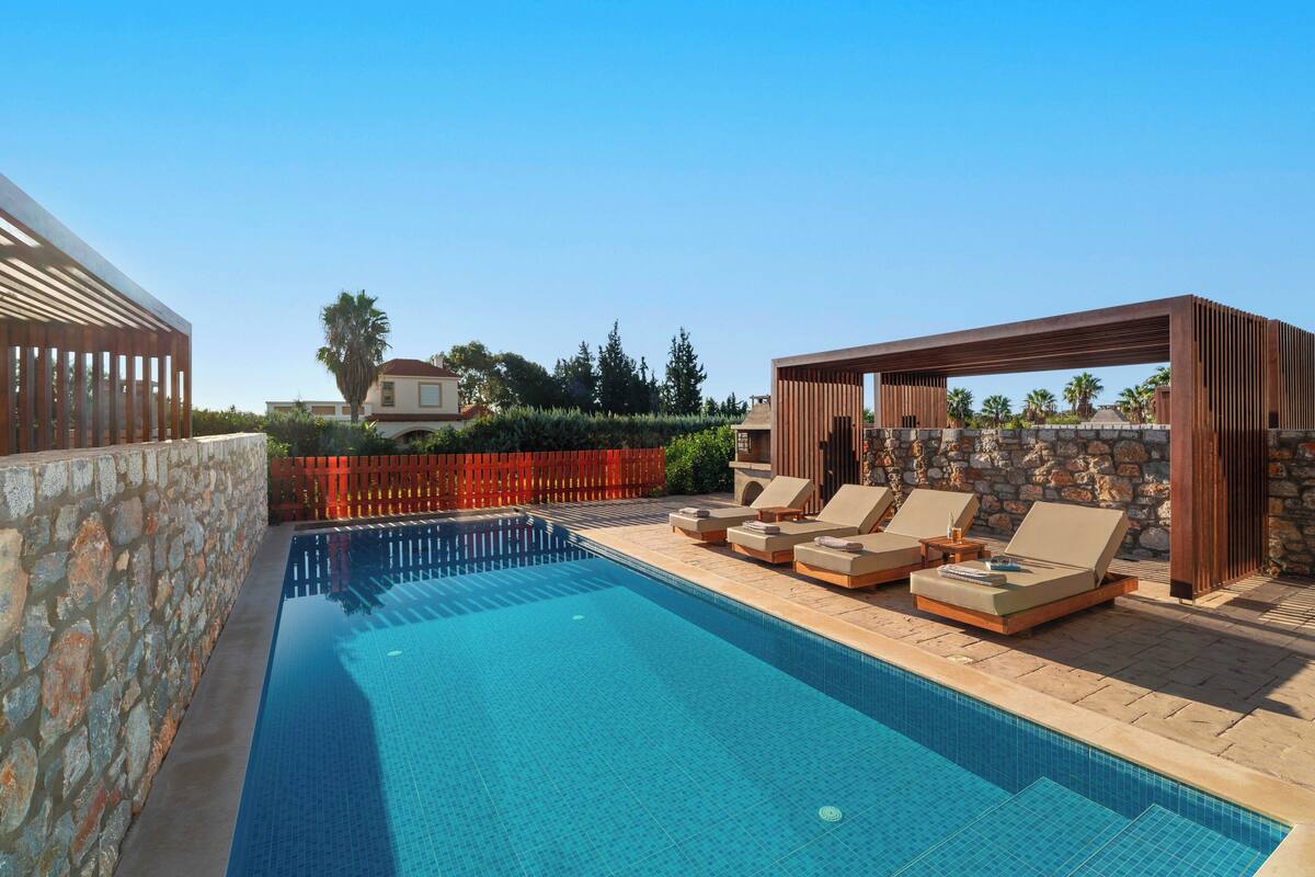 Une piscine avec des chaises longues et une pergola.