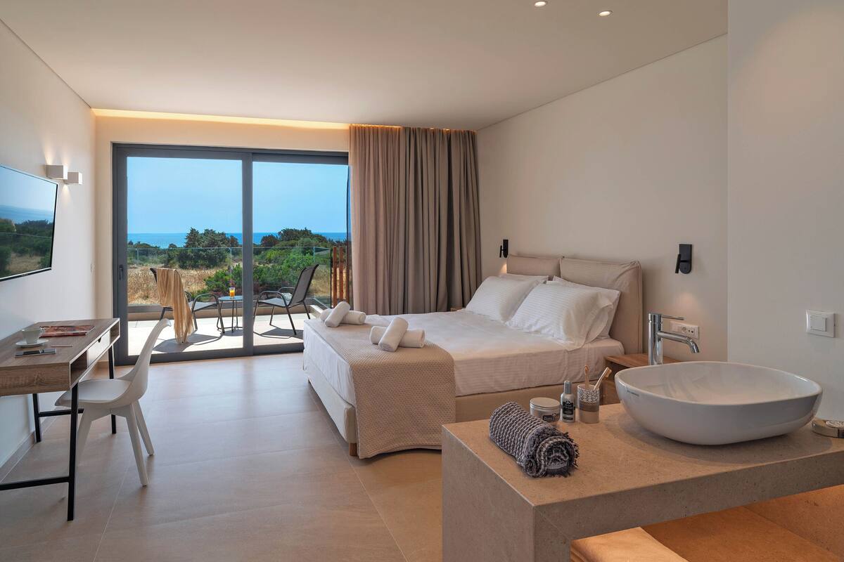 Une chambre moderne avec un grand lit, un bureau et une salle de bain dotée d’un grand lavabo.