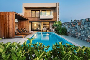 A modern house with a swimming pool, wooden deck, and stone wall. - Aethrion Luxury Villas & Suites (Rhodes)