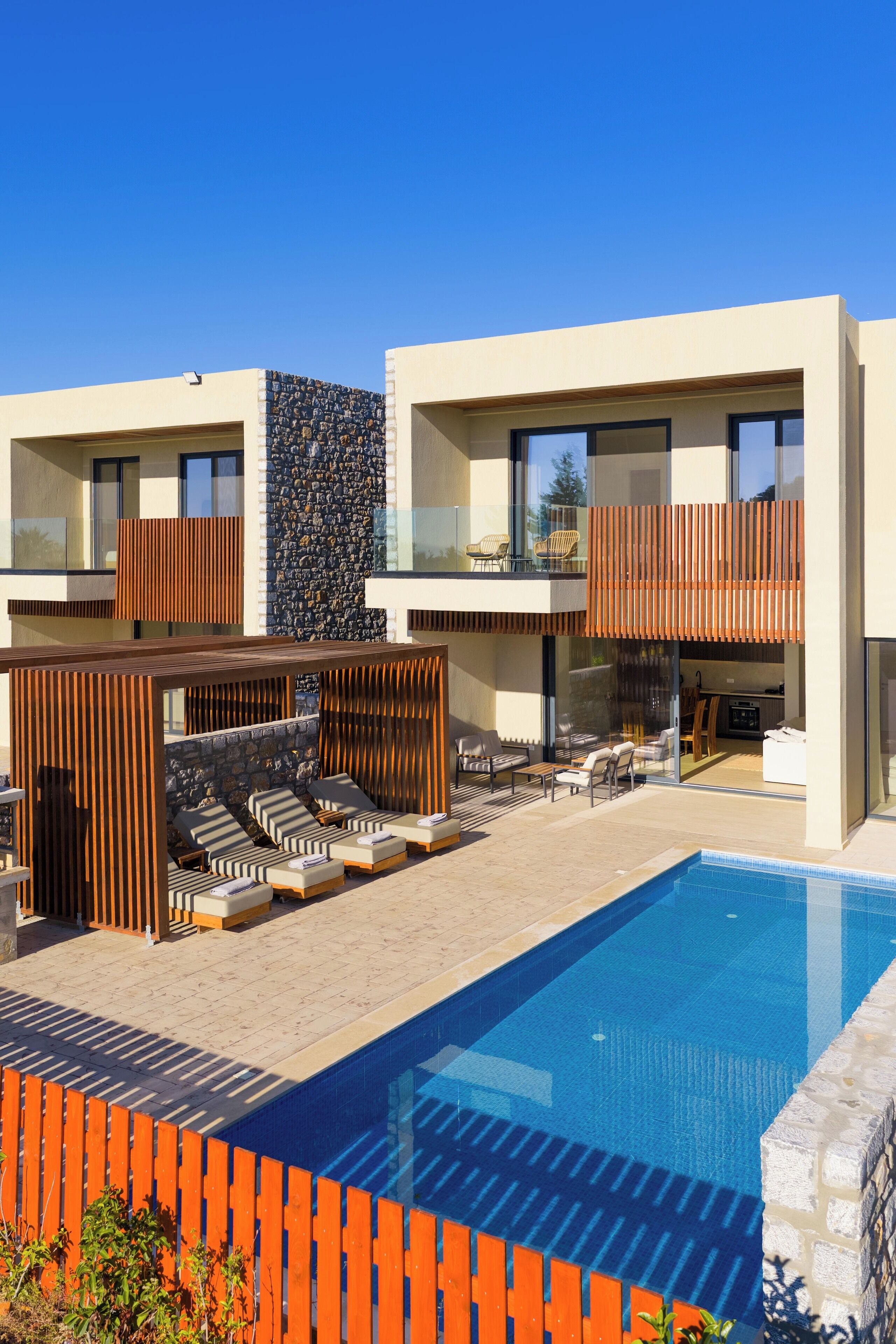 Een modern gebouw met een zwembad, terras en een stenen muur.