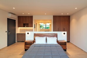 Een moderne slaapkamer met een groot bed, een houten hoofdbord, nachtkastjes en uitzicht op groen door een raam.