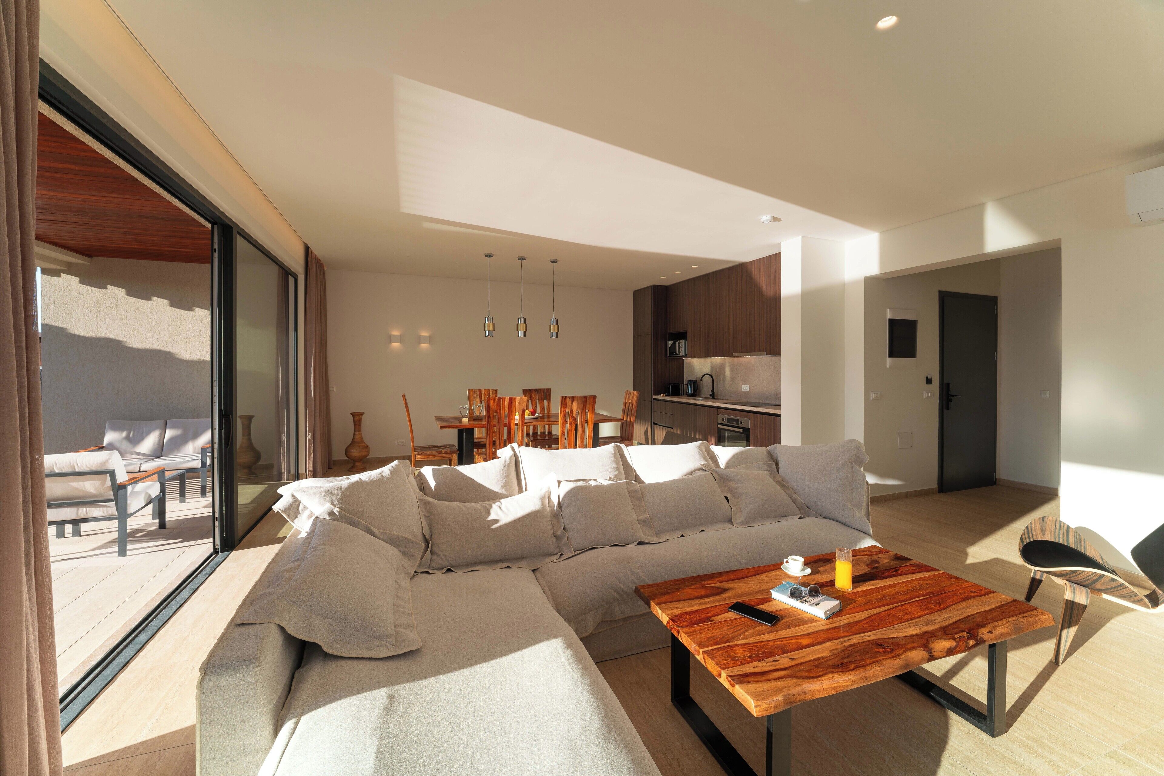 Una sala de estar moderna con un sofá modular, una mesa de centro de madera y un comedor con sillas.