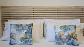 Een bed met een houten hoofdbord en twee sierkussens met een bloemenprint.