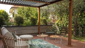 An outdoor patio with a wicker sofa, a round table, and a wicker chair. - Orio welcome (Grassobbio)