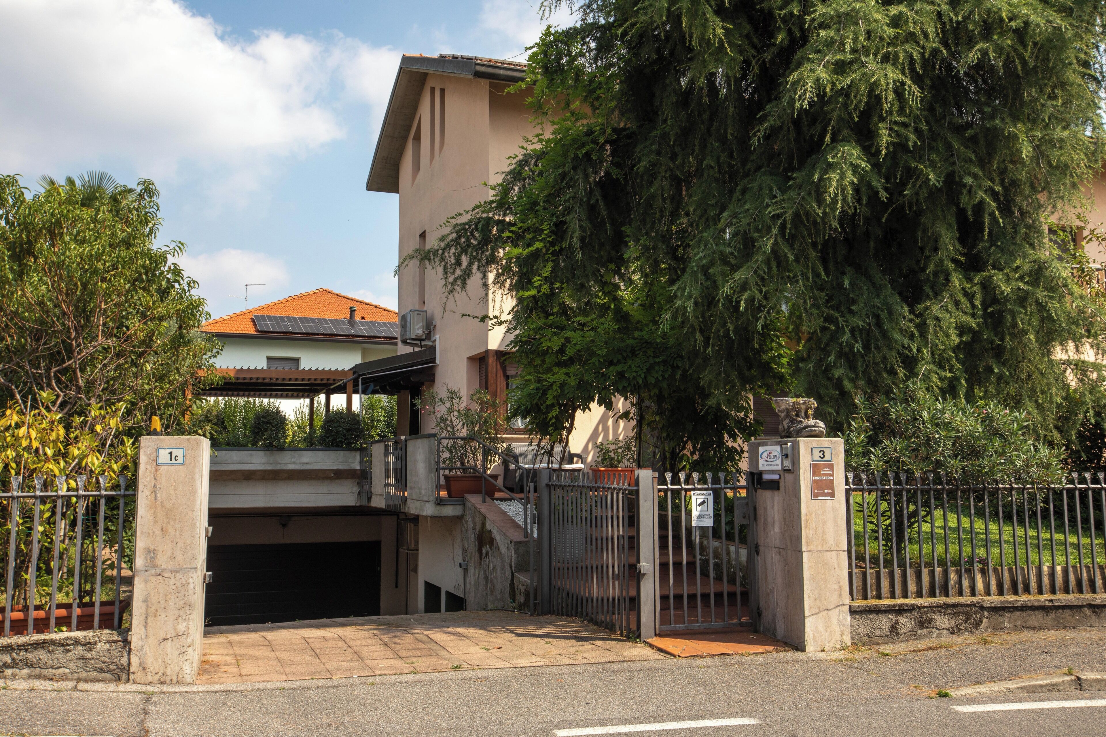 Una entrada protegida por un portón a un edificio con una escalera que conduce a un área techada.
