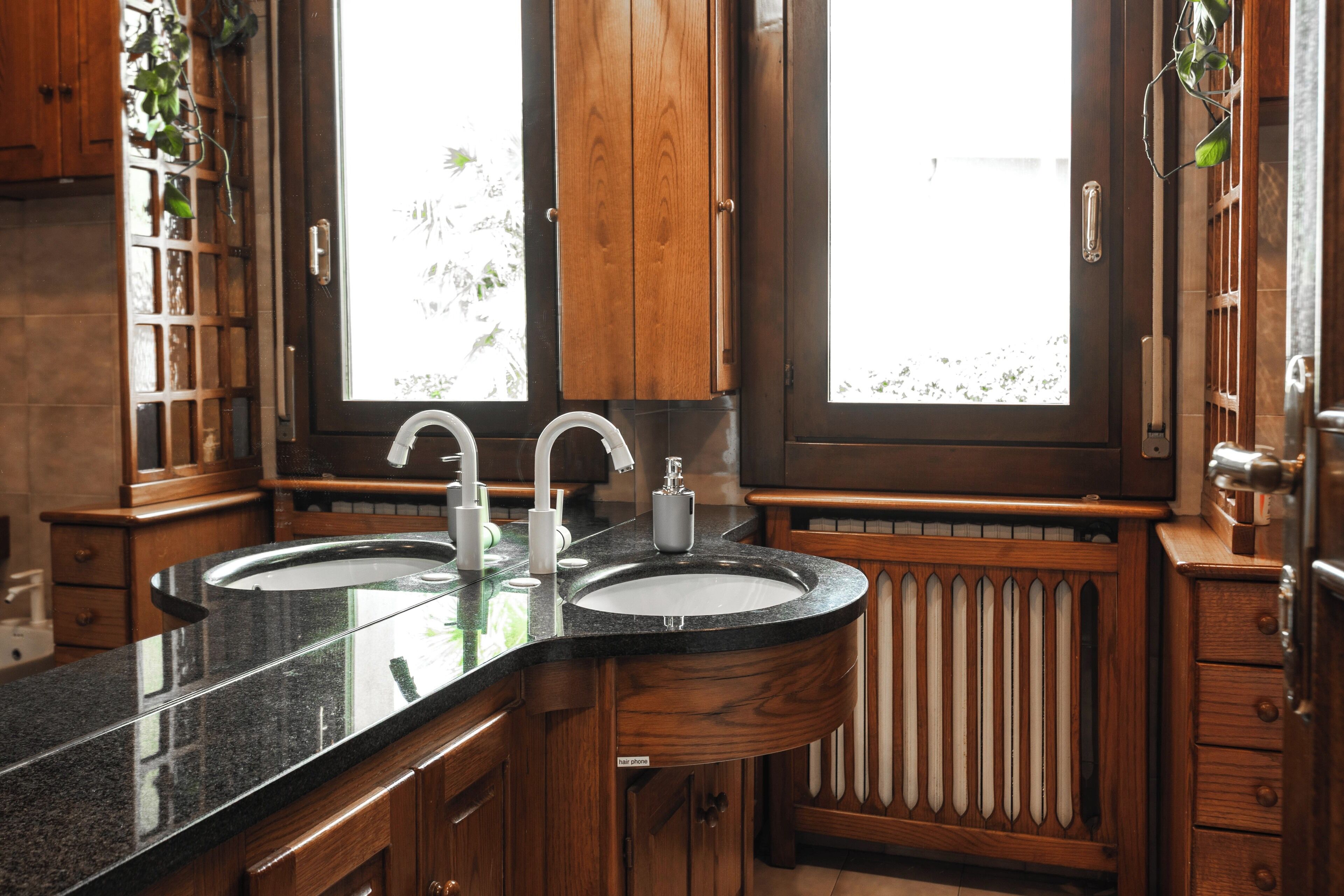 A kitchen with two sinks, wooden cabinets, and a window.