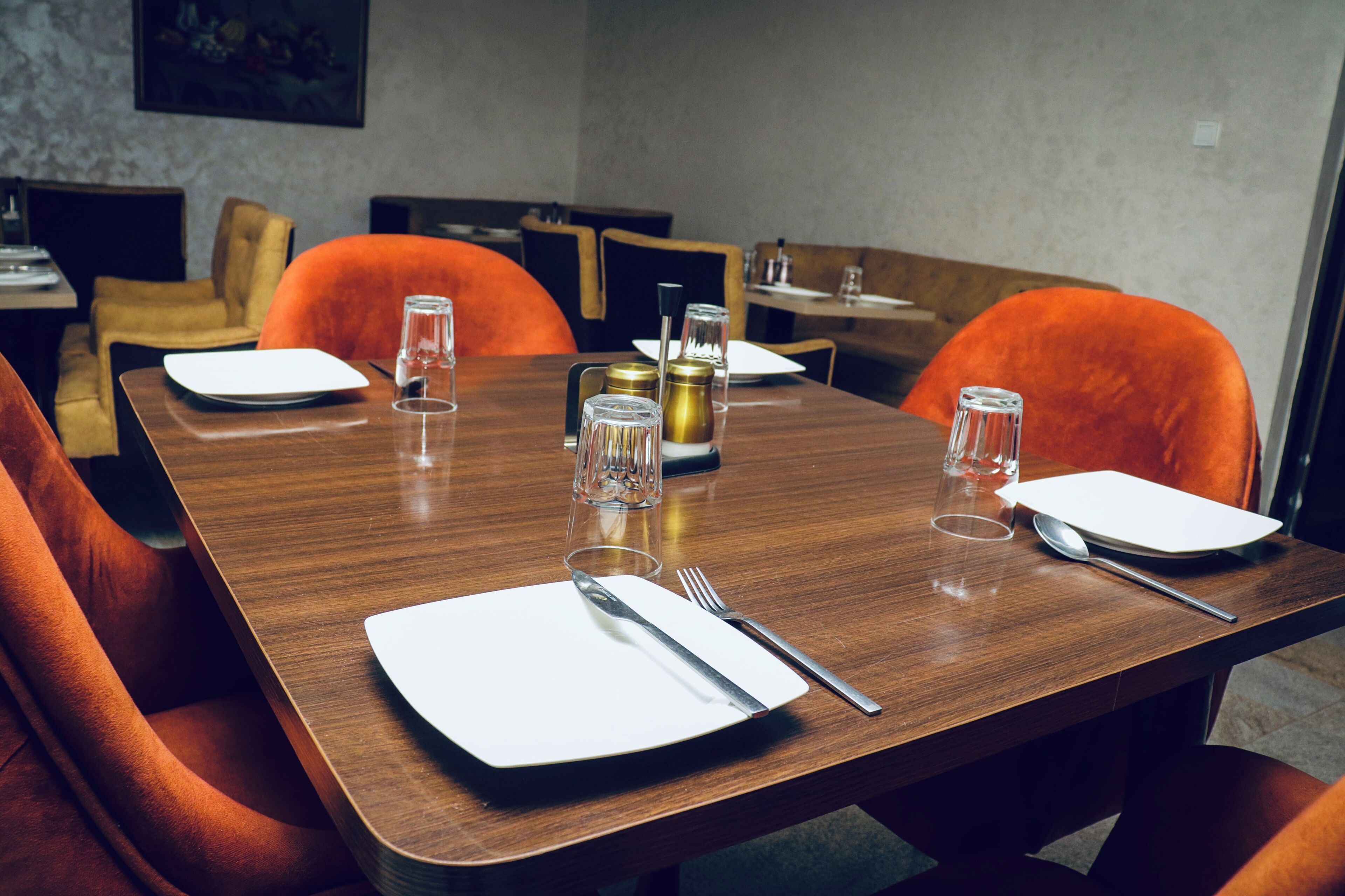 A dining area with a wooden table set for four, including plates, cutlery, and glasses.