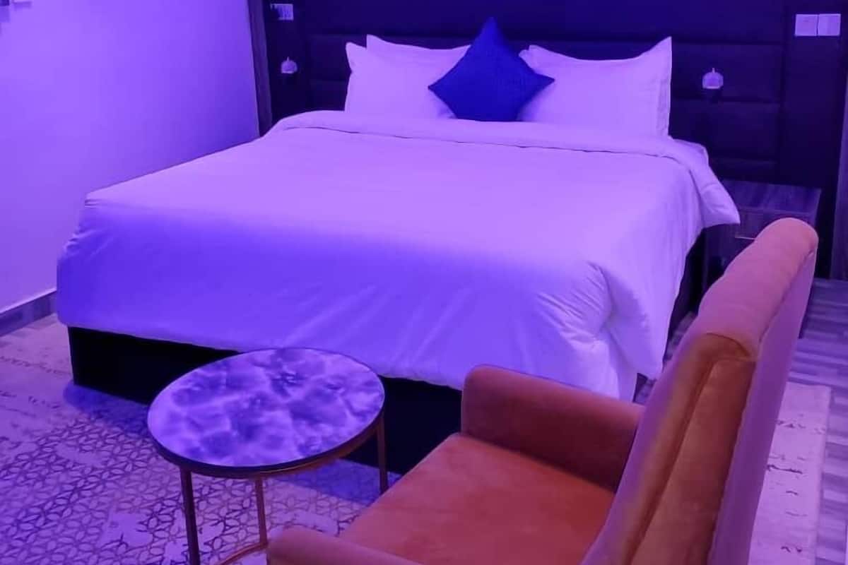 A hotel room with a bed, a small round table, and a sofa.