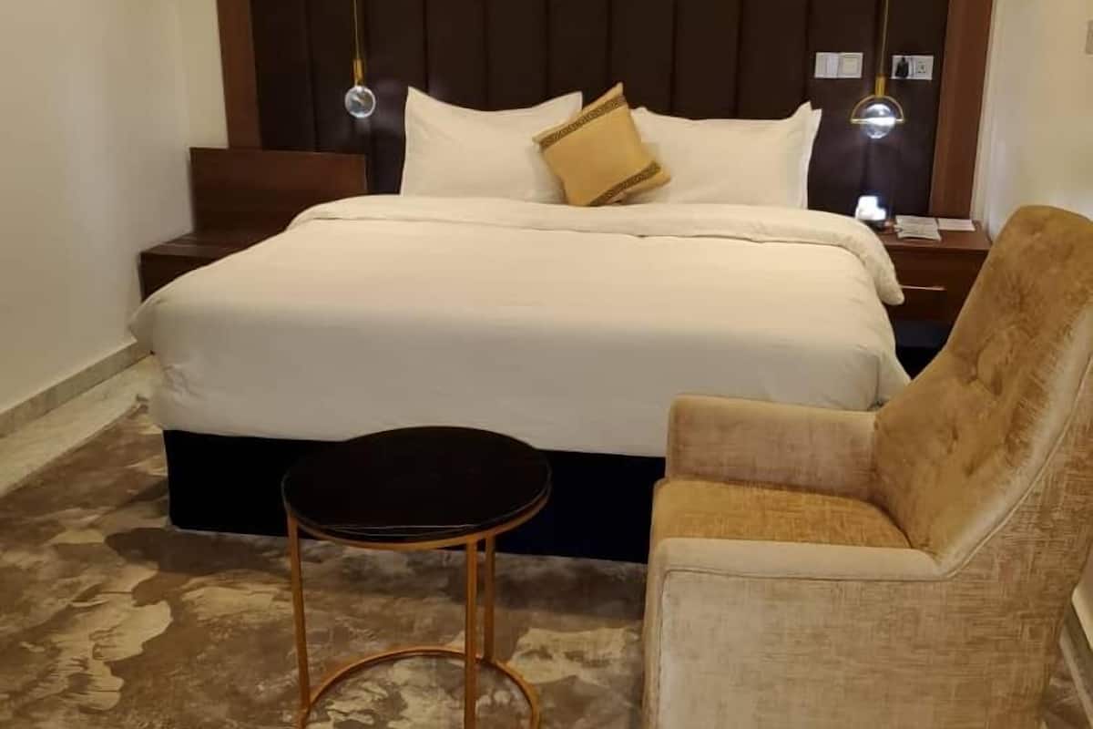 A bedroom with a large bed, a nightstand, a chair, and a small table.