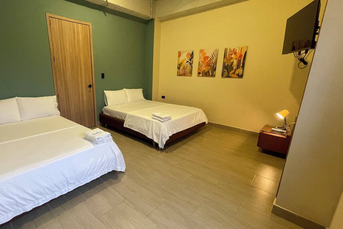 Ein Hotelzimmer mit zwei Betten, einer Holztür und einer Wand mit drei Bildern.