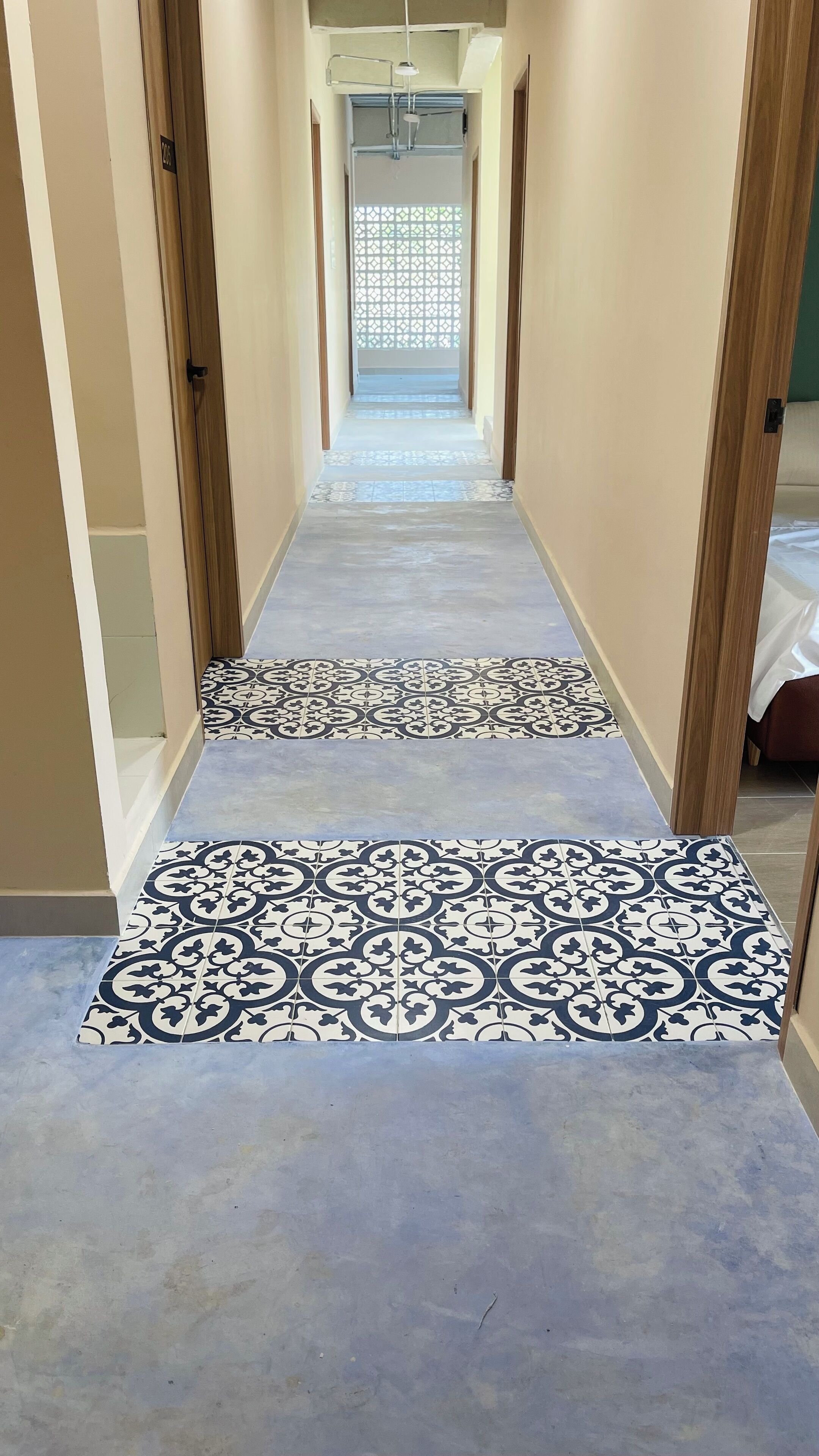 Un corridoio con piastrelle decorate a pavimento e vista su una stanza con un letto.