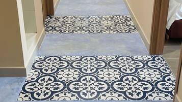 Un corridoio con piastrelle decorate a pavimento e vista su una stanza con un letto.