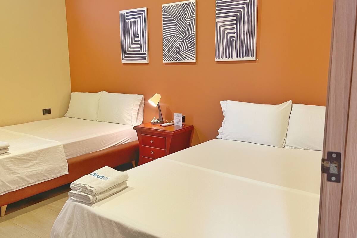 Ein Hotelzimmer mit zwei Betten, einem Nachttisch mit Lampe und drei Wandbildern.